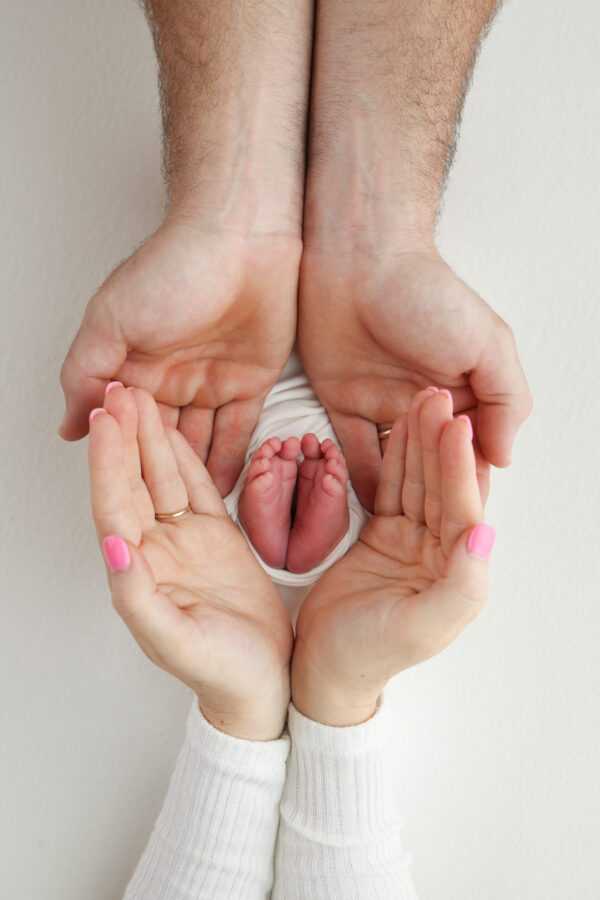 Photo showing a baby's feet in the hands of the mother and father